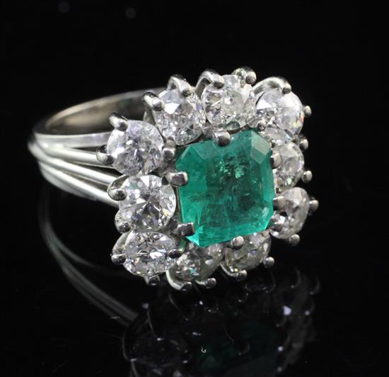 A mid to late 20th century white gold, emerald and diamond cluster dress ring, size K.